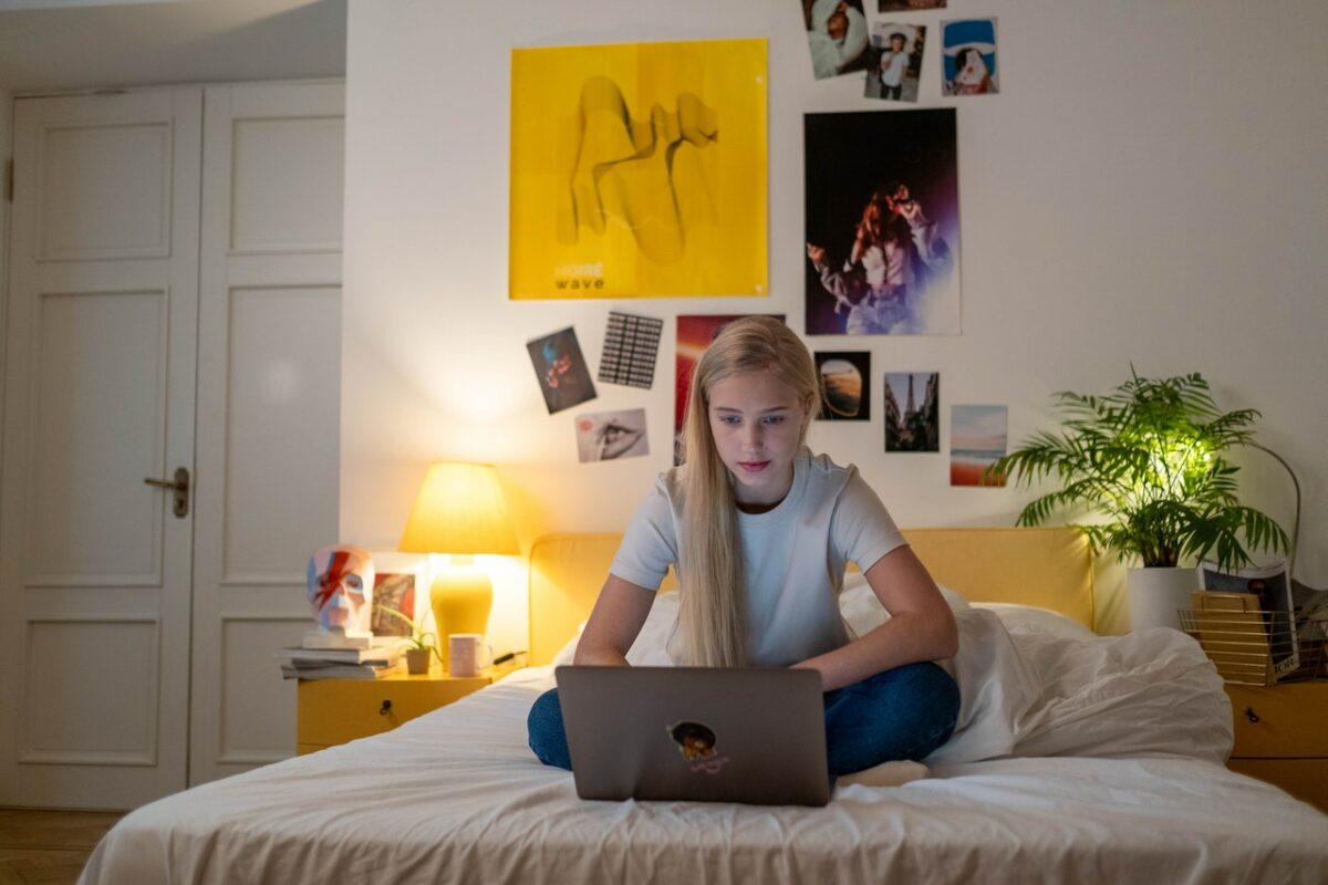 girl sitting on bed with laptop